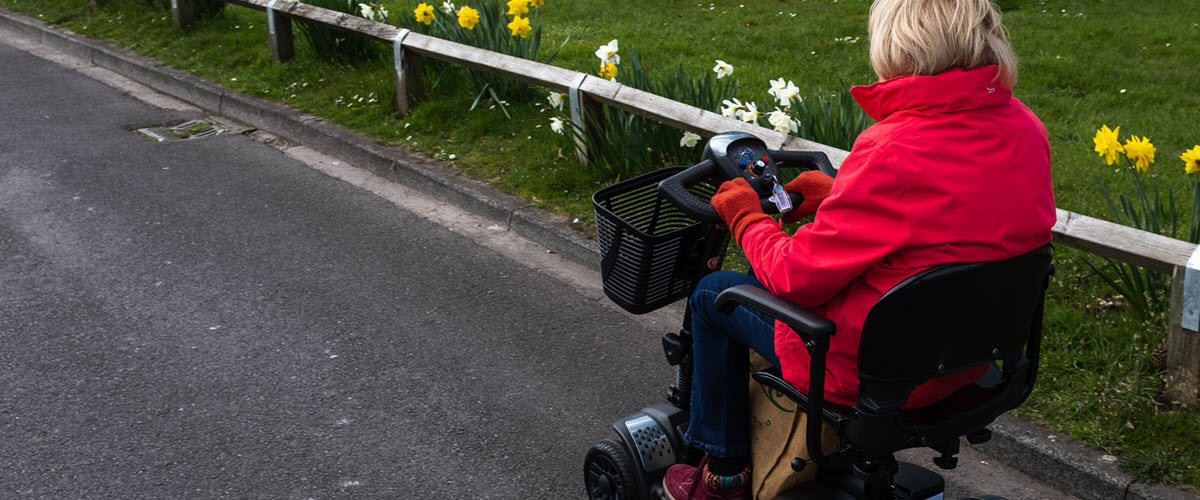 field with lady on mobility scooter on road